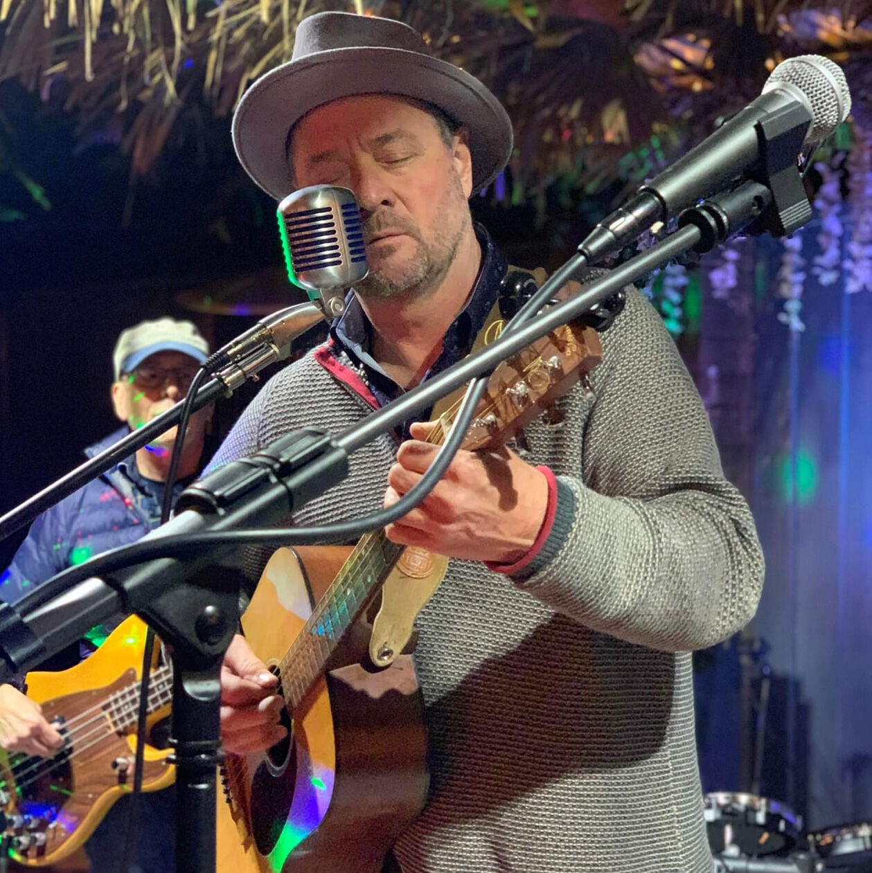 Photo of Jim Foley playing a Martin guitar behind mics